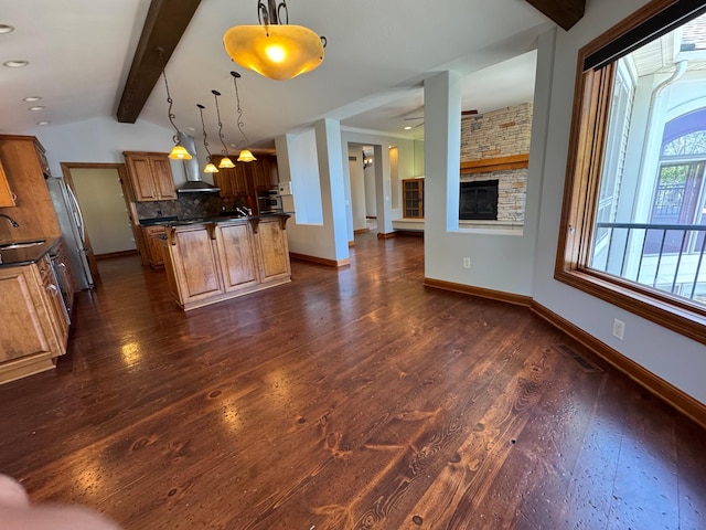 kitchen featuring dark wood-style flooring, dark countertops, backsplash, baseboards, and a sink