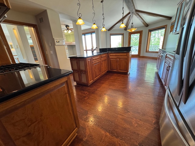 kitchen featuring freestanding refrigerator, brown cabinetry, dark wood-style floors, dark countertops, and ceiling fan