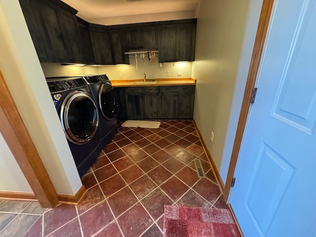 laundry area with cabinet space, washing machine and dryer, baseboards, and dark tile patterned floors