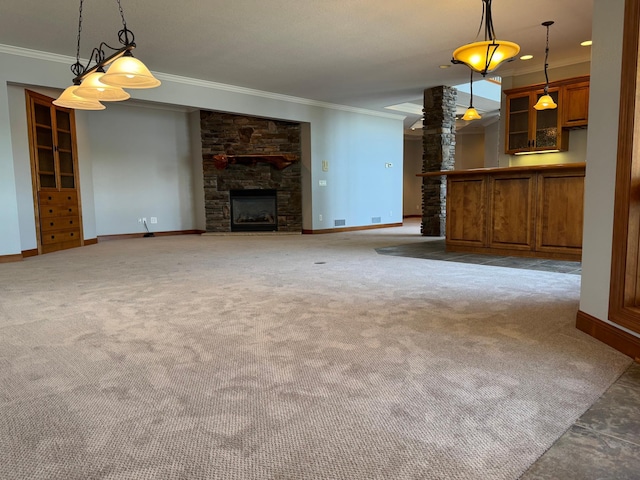unfurnished living room featuring ornamental molding, baseboards, a stone fireplace, and carpet floors