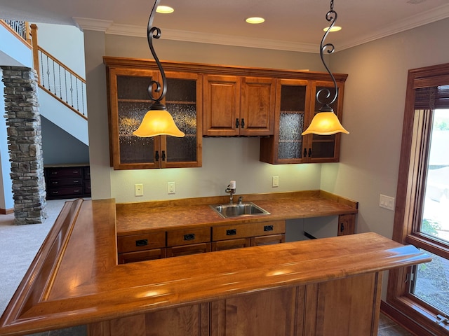 kitchen with a sink, butcher block counters, glass insert cabinets, plenty of natural light, and ornamental molding