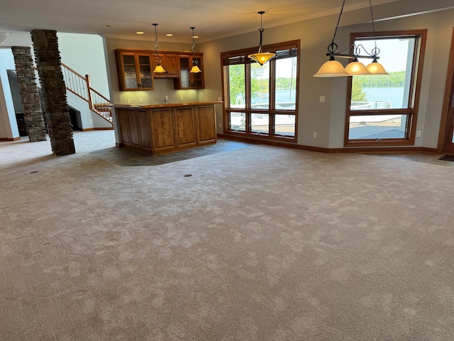 unfurnished living room featuring baseboards, crown molding, carpet flooring, stairway, and ornate columns
