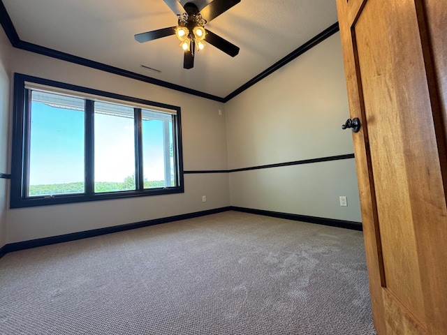carpeted empty room featuring ornamental molding, baseboards, ceiling fan, and vaulted ceiling