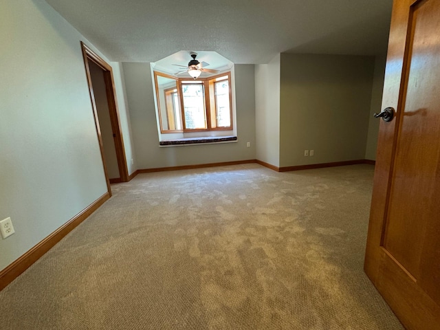 empty room with light carpet, baseboards, and a ceiling fan