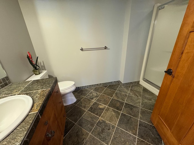 full bathroom featuring a stall shower, vanity, baseboards, and toilet