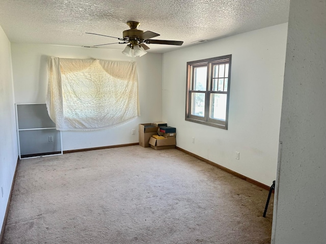 carpeted spare room featuring a textured ceiling and ceiling fan
