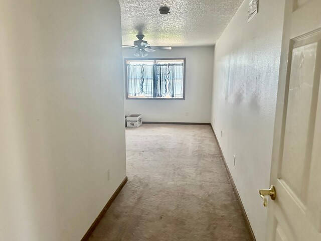 corridor with carpet flooring, a textured ceiling, and baseboards