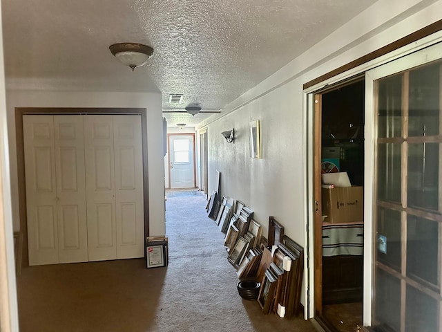 hall featuring carpet and a textured ceiling