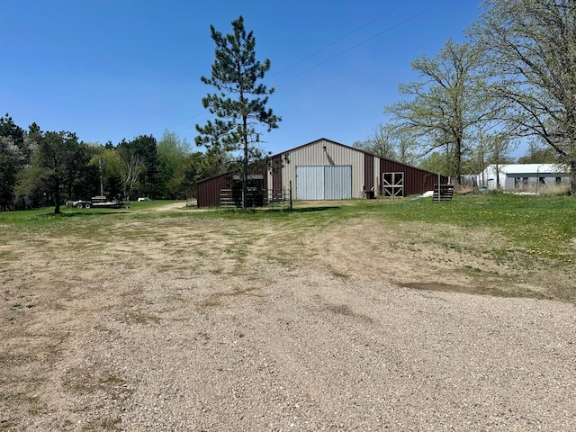 view of yard featuring an outbuilding, a detached garage, an outdoor structure, and driveway