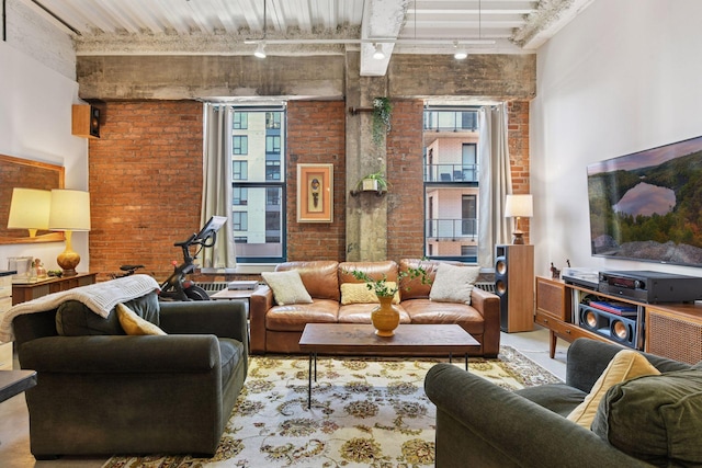 living area featuring track lighting, brick wall, and a towering ceiling