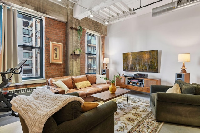 living area with brick wall, rail lighting, and a high ceiling