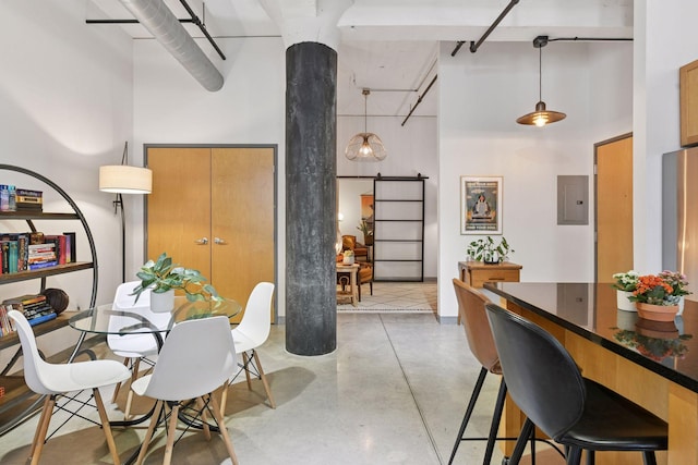dining space with a high ceiling, concrete flooring, a barn door, and electric panel
