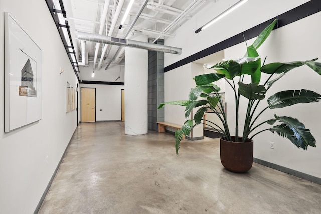 hall featuring concrete flooring and baseboards