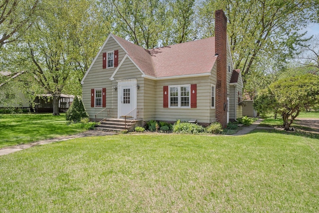 view of front of property with roof with shingles, a chimney, and a front yard