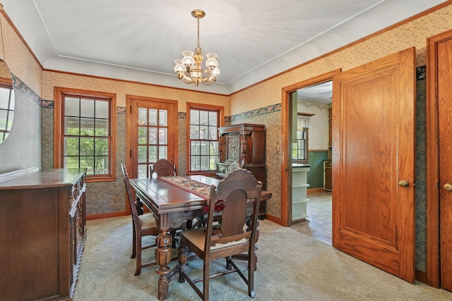 dining space featuring wallpapered walls, healthy amount of natural light, a chandelier, crown molding, and carpet flooring
