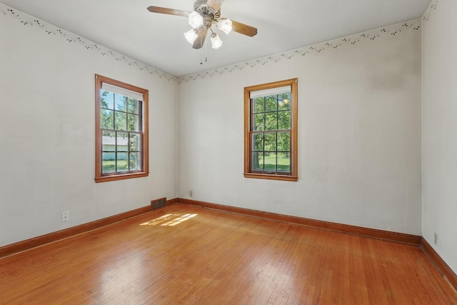 empty room featuring healthy amount of natural light, light wood-type flooring, and baseboards