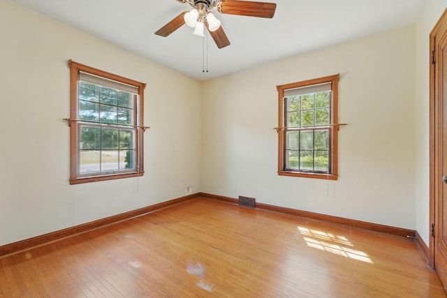spare room featuring plenty of natural light, light wood-type flooring, baseboards, and ceiling fan