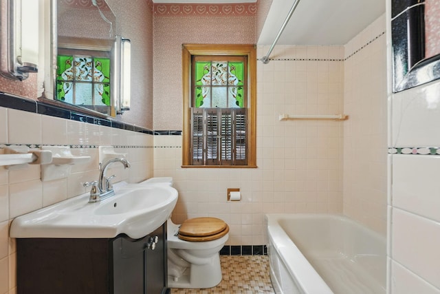 full bathroom with tile walls, toilet, vanity, and shower / bathtub combination