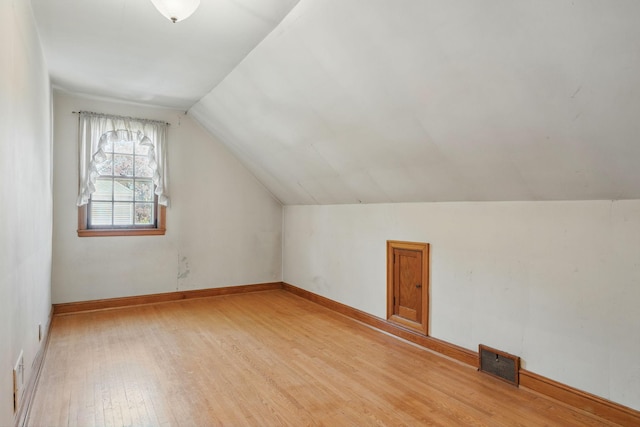 additional living space featuring light wood-style floors, lofted ceiling, and baseboards