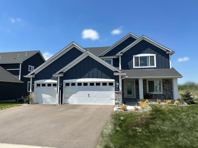 craftsman-style house featuring board and batten siding, stone siding, asphalt driveway, and a garage