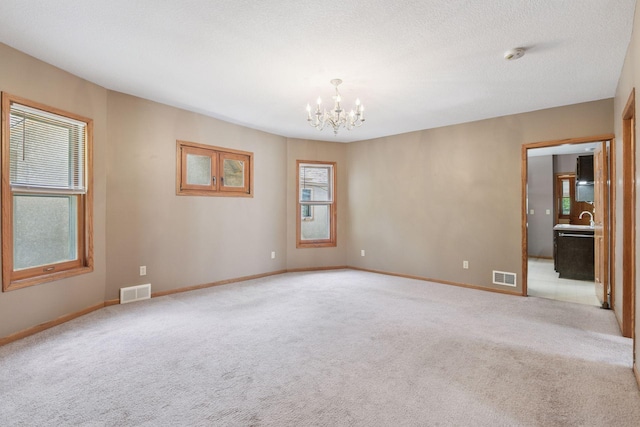 716 4th St NE, Minneapolis, MN 55413 - empty room featuring light colored carpet, a chandelier, baseboards, a smoke detector, and a sink
