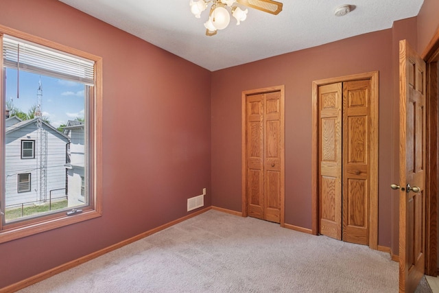 716 4th St NE, Minneapolis, MN 55413 - unfurnished bedroom featuring light carpet, two closets, and baseboards