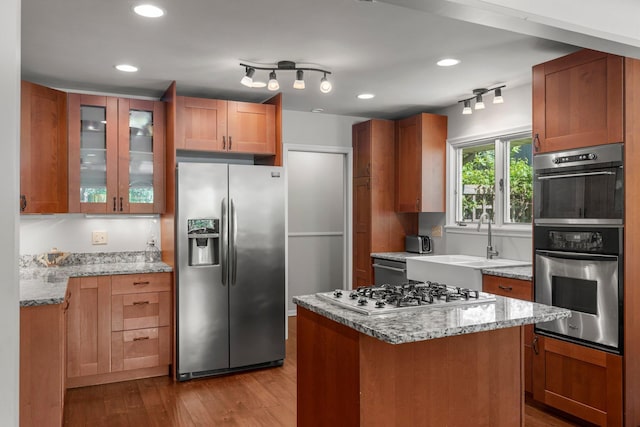2532 Upton Ave S, Minneapolis, MN 55405 - kitchen with appliances with stainless steel finishes, wood finished floors, glass insert cabinets, light stone counters, and recessed lighting
