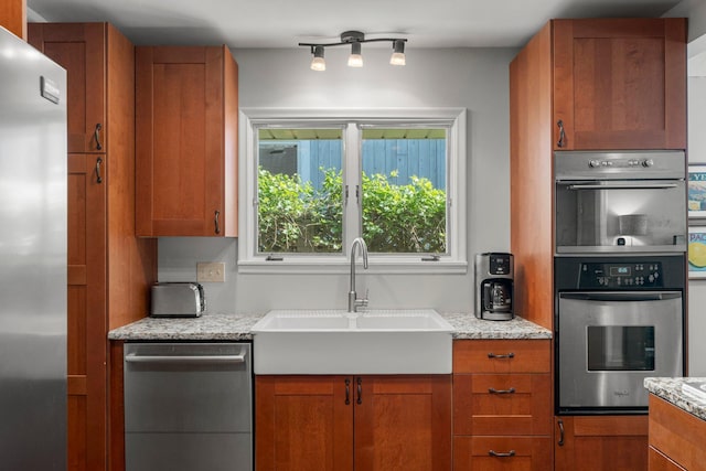 2532 Upton Ave S, Minneapolis, MN 55405 - kitchen featuring stainless steel appliances, a sink, brown cabinets, and light stone counters