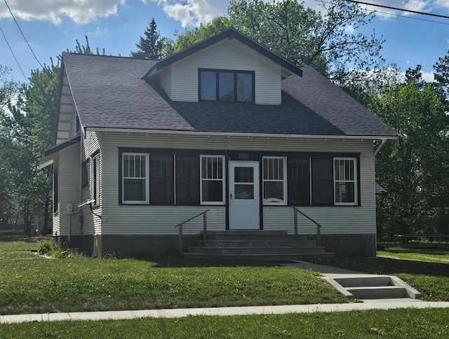 view of front facade with a front lawn, entry steps, and roof with shingles