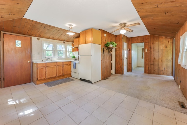kitchen featuring white appliances, lofted ceiling, wooden walls, a ceiling fan, and light countertops