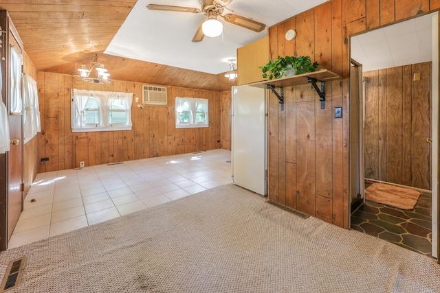 empty room featuring wooden walls, a wall mounted air conditioner, vaulted ceiling, a ceiling fan, and tile patterned flooring