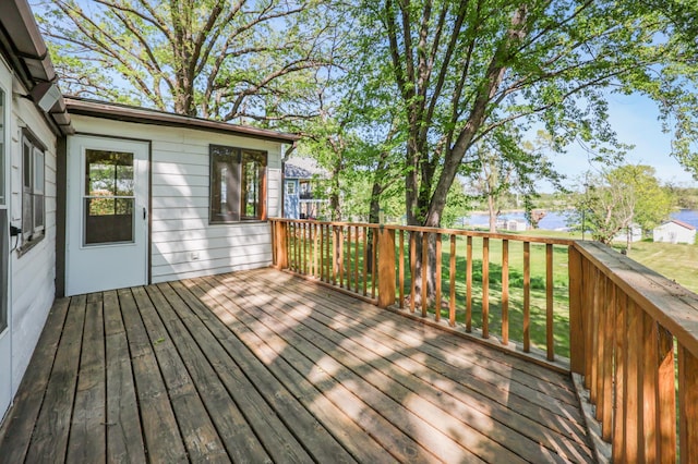 wooden deck with a water view and a lawn