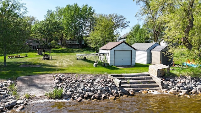 view of property's community with an outdoor structure, a storage shed, a yard, a detached garage, and a water view