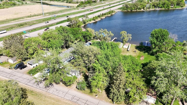 drone / aerial view of a nearby body of water, a highway, and a tree filled landscape