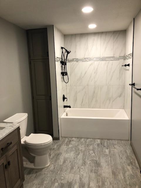 bathroom with toilet, vanity, shower / washtub combination, wood finished floors, and recessed lighting