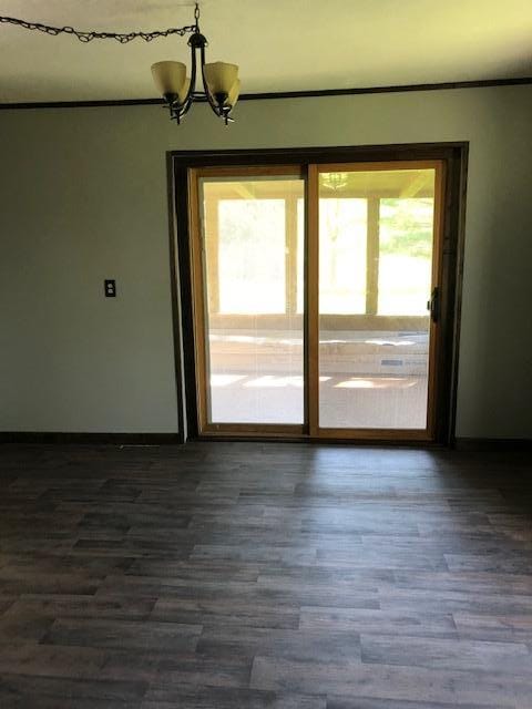unfurnished dining area with a chandelier, dark wood-style flooring, and baseboards