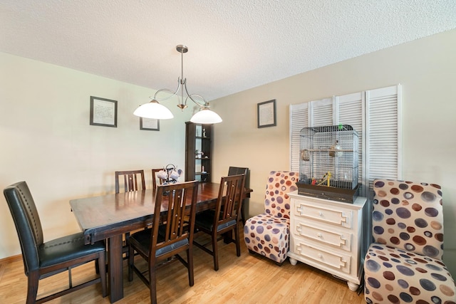 dining space with light wood-style floors and a textured ceiling