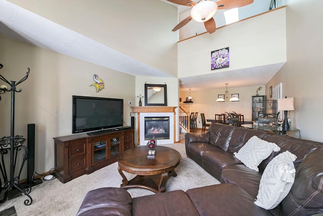 carpeted living room featuring ceiling fan, a glass covered fireplace, and baseboards