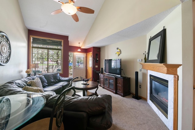 living area featuring light carpet, vaulted ceiling, a ceiling fan, and a high end fireplace