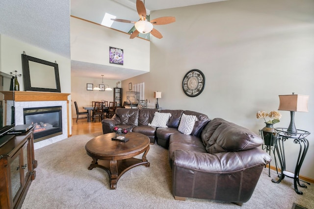 living room with a ceiling fan, a tile fireplace, and baseboards