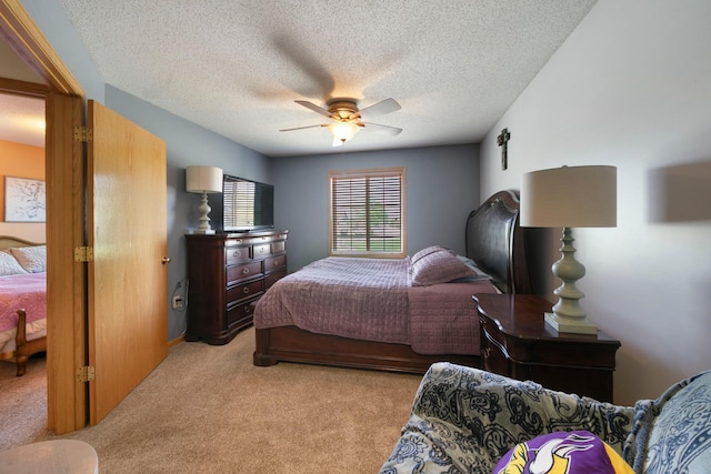 bedroom with light colored carpet, ceiling fan, and a textured ceiling