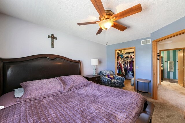 carpeted bedroom with a walk in closet, a closet, ceiling fan, and a textured ceiling