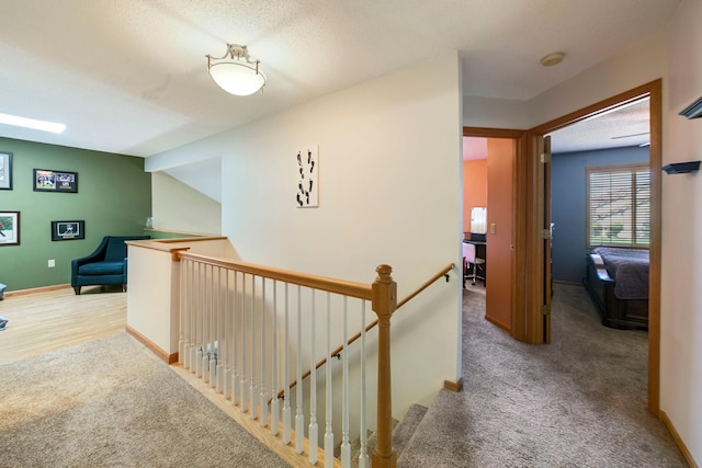 corridor with an upstairs landing, carpet, and baseboards