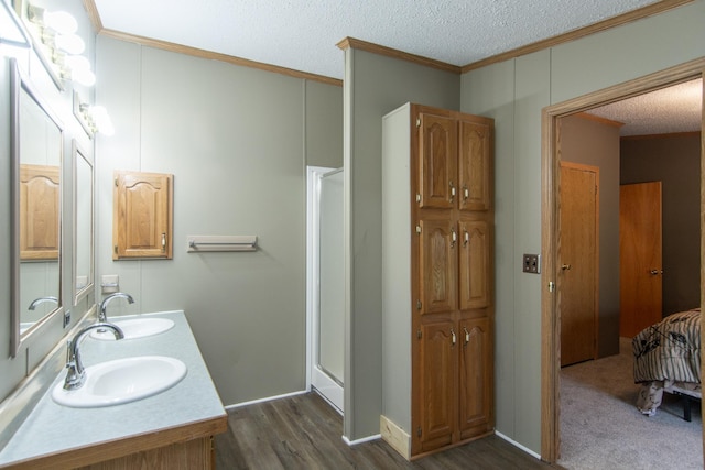 full bathroom featuring ornamental molding, a shower stall, a textured ceiling, wood finished floors, and double vanity