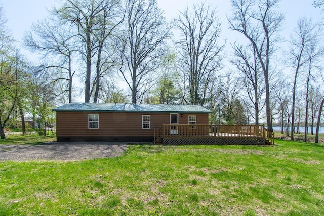 back of house featuring log veneer siding, a deck with water view, a yard, and metal roof