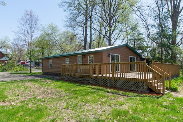 rear view of house featuring a deck, faux log siding, and a yard