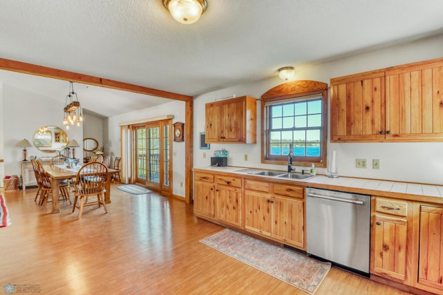 kitchen featuring dishwasher, tile countertops, light wood-style flooring, plenty of natural light, and a textured ceiling
