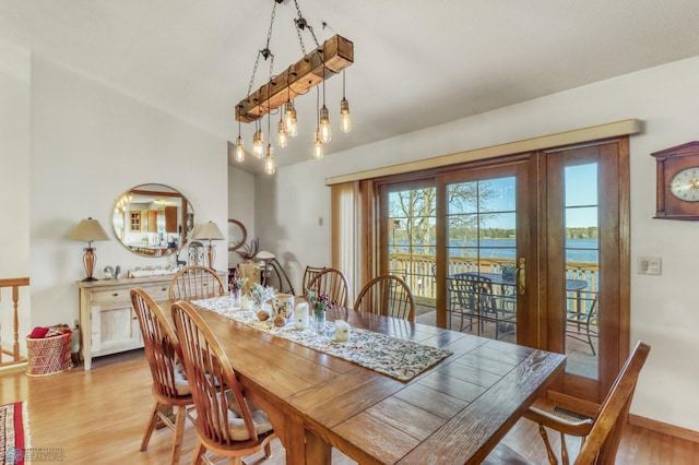 dining space with light wood finished floors, vaulted ceiling, baseboards, and a chandelier