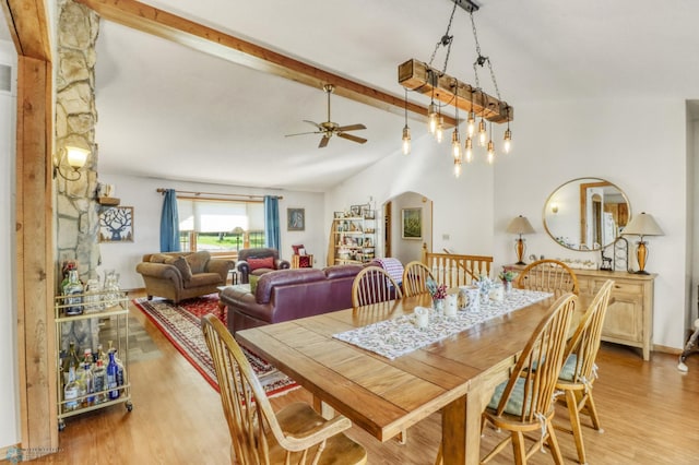 dining area featuring a ceiling fan, light wood finished floors, and arched walkways