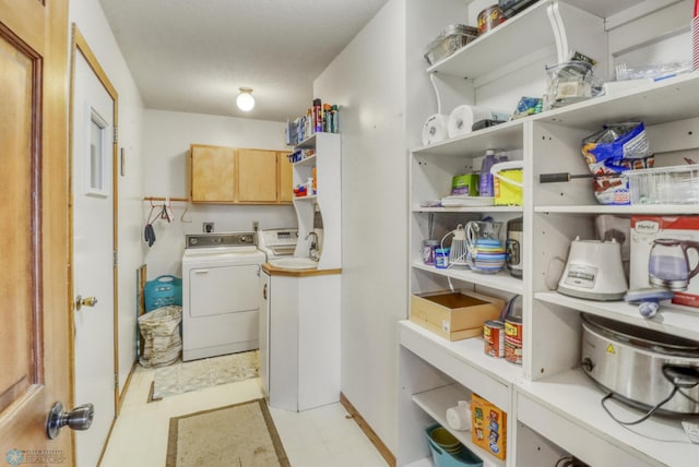 clothes washing area with washer / dryer, cabinet space, and light floors